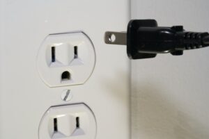 A black plug being inserted in a power outlet