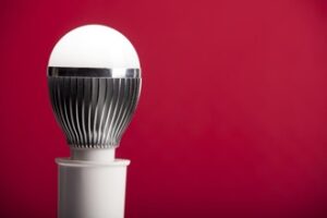 An LED bulb on a holder in front of a red background