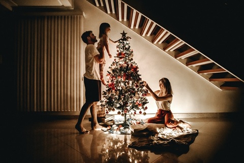 a family decorating a Christmas tree safely