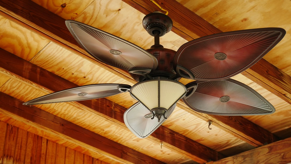 A ceiling fan on a wooden ceiling.